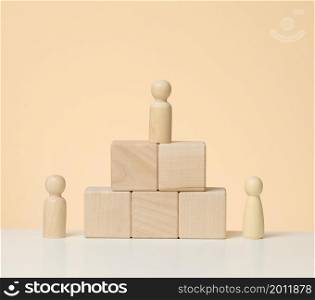 wooden figures of men stand on a pedestal of their cubes. The concept of rivalry in sports, business and life. Achieving success and leadership