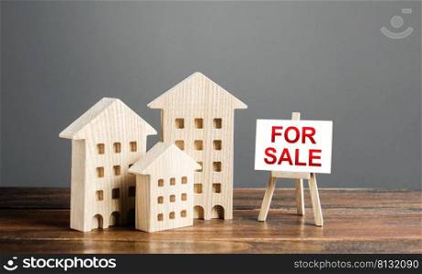Wooden figures of residential buildings and an easel sign labeled for sale. Buying and selling real estate, hot offers and property valuation. Smart investments and relocation. Good offer