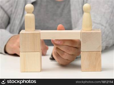 wooden figures stand on the bridge from the sides opposite each other, concept of finding a compromise, constructive dialogue, business opponents