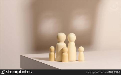 wooden figurines of a family on a background of shadow in the form of a house. Beige background. Home dreams, mortgage
