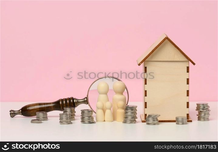 wooden figurines of a family, stacks of metal money, a miniature wooden house. Real estate purchase, mortgage concept. Accumulation of funds