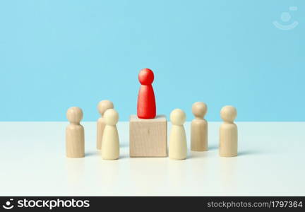 wooden figurines of men on a blue background. Public speaking concept, leadership and discussion. The team unites around an idea, cooperation