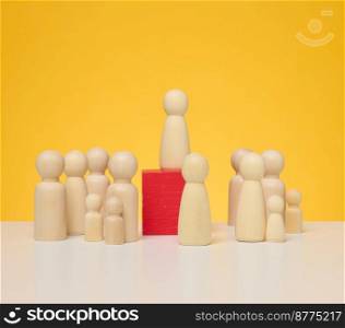 Wooden figurines of men on a yellow background. Public speaking concept, leadership and discussion. The team unites around an idea, cooperation