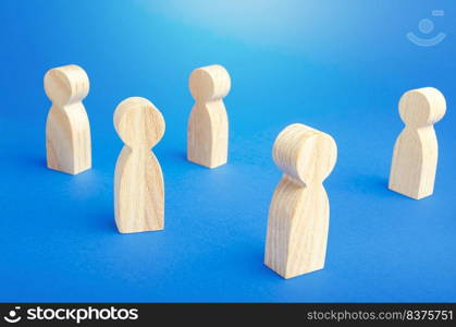 Wooden figurines of people stand on a blue background. Loneliness and disconnection. Safe spacing between persons, new normal. Faceless mass. Communication. Society public. Disunity concept.