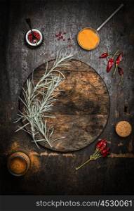 Wooden food background with old dark chopping cutting board, herbs and spices, top view