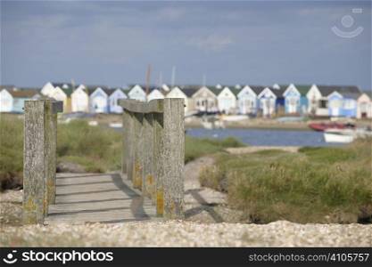 Wooden foot bridge with beach huts in background