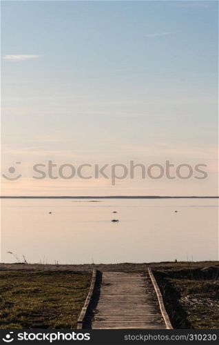 Wooden footbridge by the coast with absolutely calm water at the swedish island Oland