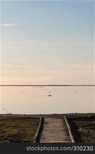 Wooden footbridge by the coast with absolutely calm water at the swedish island Oland