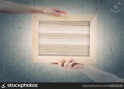 Wooden frame. Close up of hands holding wooden blank frame. Place for text