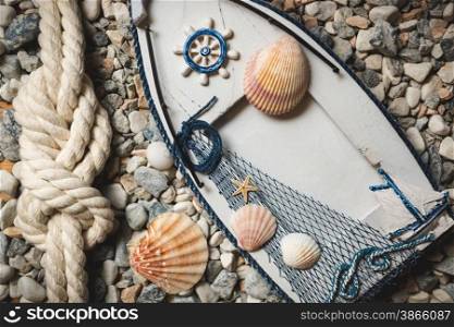 Wooden frame decorated by shells and ropes lying on stones at shore