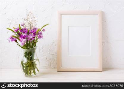 Wooden frame mockup with purple burdocks in jug. Wooden frame mockup with purple burdock flowers in the glass jug. Empty frame mock up for presentation design. Template framing for modern art.