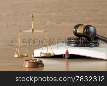 Wooden gavel, golden scales of justice and books on wood background