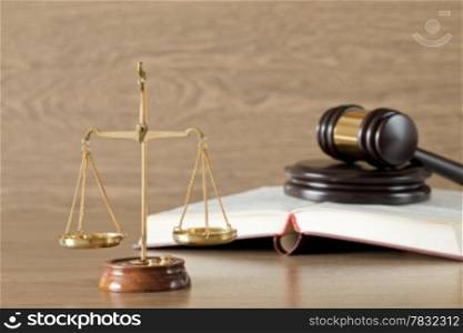 Wooden gavel, golden scales of justice and books on wood background