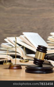 Wooden gavel, golden scales of justice and books on wood background