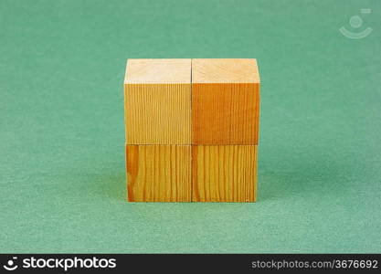 wooden geometric cube on a green background