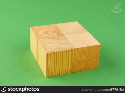 wooden geometric cube on a green background