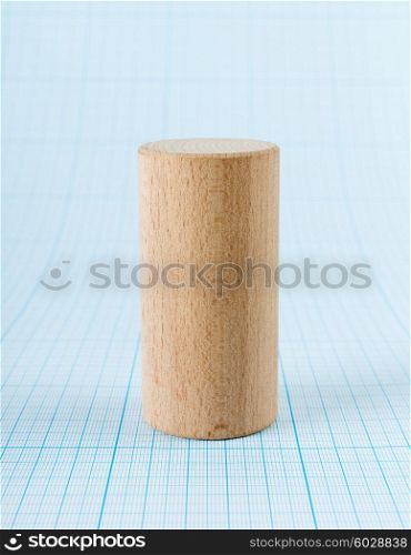 Wooden geometric shape cylinder on graph paper