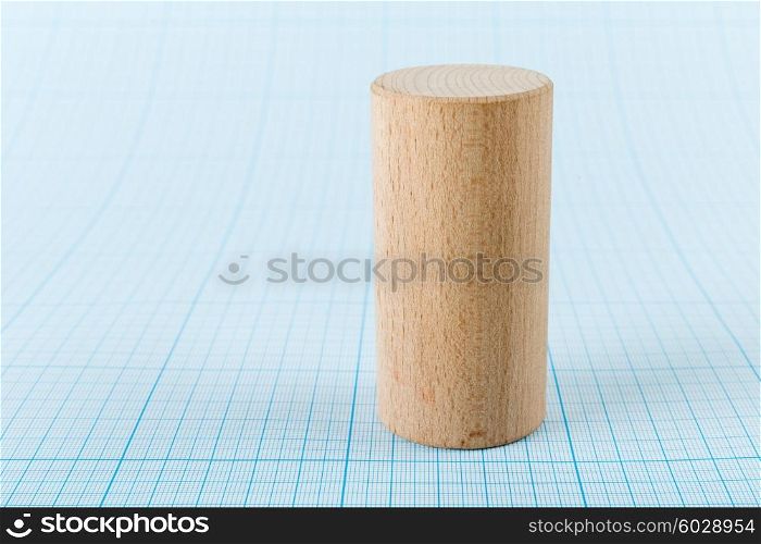 Wooden geometric shape cylinder on graph paper