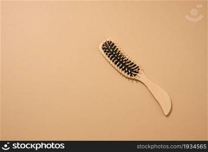 wooden hair comb on brown background, zero waste. Top view