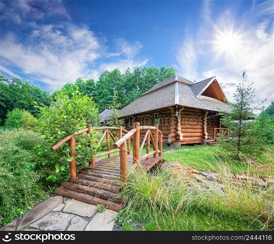 Wooden house and bridge among greenery under the bright sun. Wooden house and bridge among greenery under bright sun