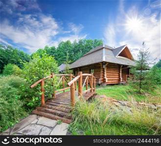 Wooden house and bridge among greenery under the bright sun. Wooden house and bridge among greenery under bright sun