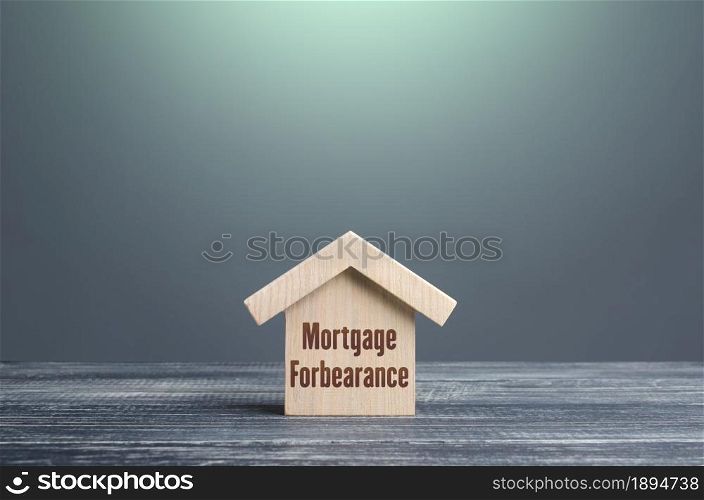 Wooden house figurine with inscription Mortgage forbearance. Borrower and lender agreements reduce or suspend mortgage loan payments for period of time. Financial relief measures. Prolongation