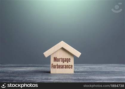 Wooden house figurine with inscription Mortgage forbearance. Borrower and lender agreements reduce or suspend mortgage loan payments for period of time. Financial relief measures. Prolongation