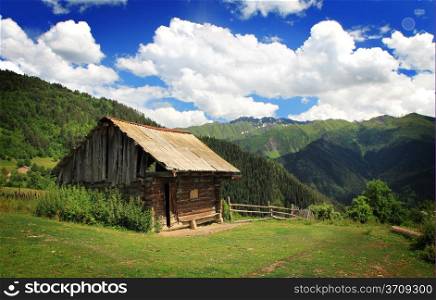 Wooden house in mountains on blue clody sky background