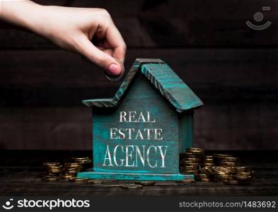 Wooden house model with coins next to it and hand holding the coin with conceptual text. End Financing