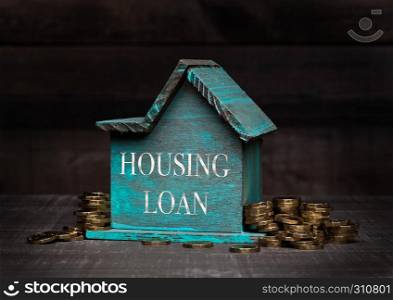 Wooden house model with coins next to it with conceptual text. Housing Loan
