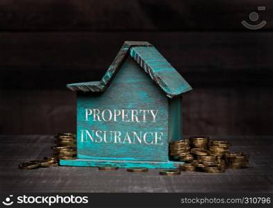 Wooden house model with coins next to it with conceptual text. Property Insurance