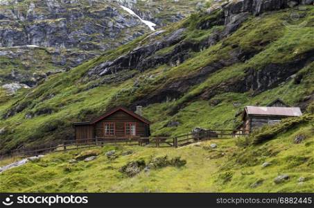 wooden house on the hills of the Jostedalsbreen nature park in summer with snow on the mountains