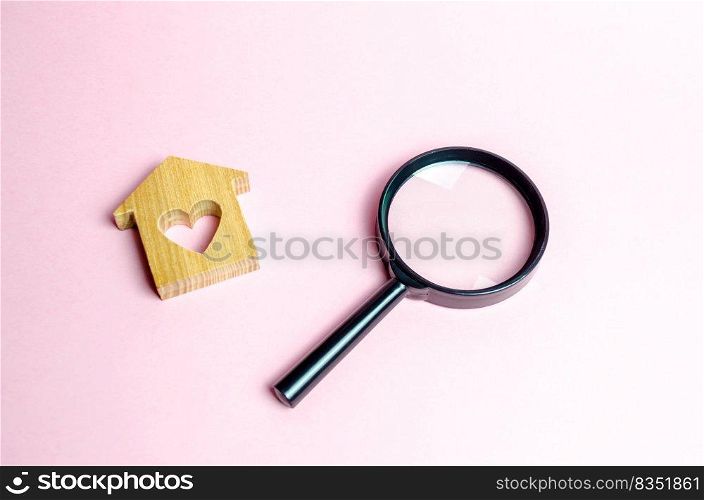 Wooden house with a heart and a magnifying glass. Search and purchase of affordable housing for young families and married couples. Mortgage. Rent a home for a romantic holiday on Valentine’s Day.