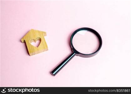 Wooden house with a heart and a magnifying glass. Search and purchase of affordable housing for young families and married couples. Mortgage. Rent a home for a romantic holiday on Valentine&rsquo;s Day.