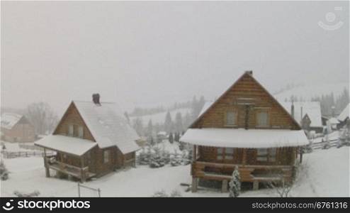 Wooden houses and falling snow with moving camera