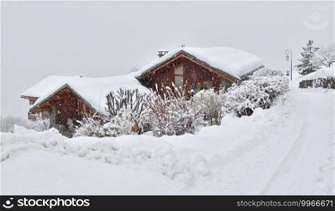 wooden houses covered with snow  in alpine mountain village under snowfall . wooden housescovered with snow  in alpine mountain village under snowfall 