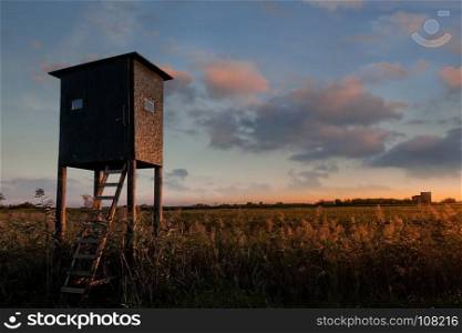 Wooden hunter tower high seat. Raised shed hunting.