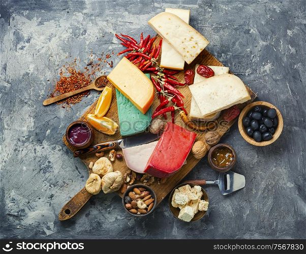 Wooden kitchen board with different kinds of delicious cheese on table. Delicious cheese on the table