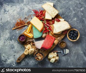 Wooden kitchen board with different kinds of delicious cheese on table. Delicious cheese on the table