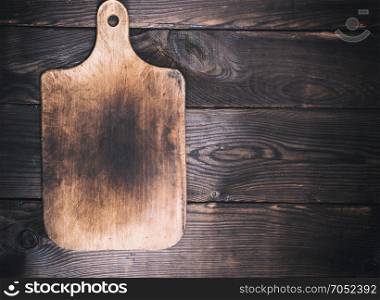 wooden kitchen cutting board on brown background, empty space on the right