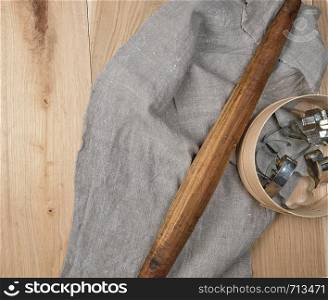 wooden kitchen items rolling pin, sieve on a gray linen towel, top view