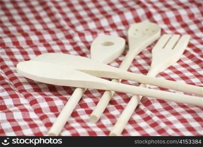 Wooden kitchen utensils over red and white cloth fabric