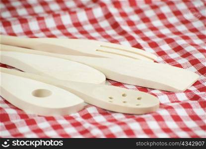 Wooden kitchen utensils over red and white cloth fabric