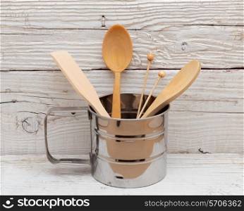 wooden kitchenware in metal mug on old table