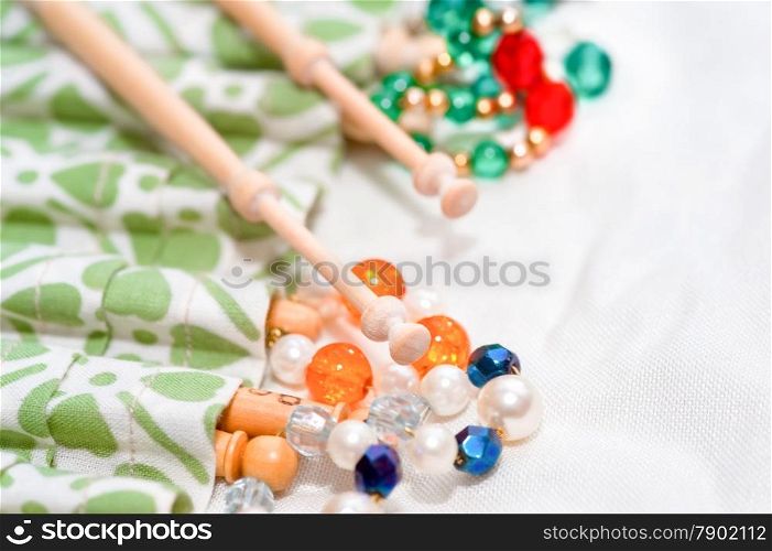 wooden lacemaking bobbins and decorative beads on white linen