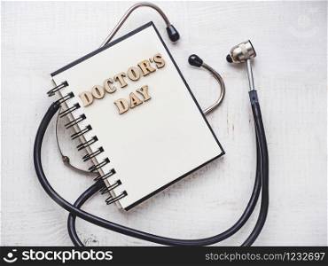 Wooden letters of the alphabet in the form of the words DOCTOR&rsquo;S DAY lying on a white table. Beautiful card. Isolated background, wooden surface. Congratulations for relatives, friends and colleagues. Happy Doctor&rsquo;s Day. Beautiful greeting card. Isolated background