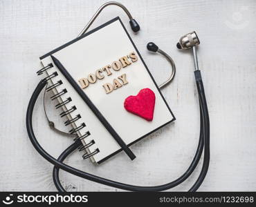 Wooden letters of the alphabet in the form of the words DOCTOR&rsquo;S DAY lying on a white table. Beautiful card. Isolated background, wooden surface. Congratulations for relatives, friends and colleagues. Happy Doctor&rsquo;s Day. Beautiful greeting card. Isolated background