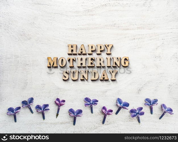 Wooden letters of the alphabet in the form of the words Mothering Sunday lying on the table. View from above. Isolated background, wooden surface. Congratulations for relatives, friends, colleagues. Mothering Sunday. Card. View from above. Close up