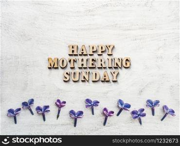 Wooden letters of the alphabet in the form of the words Mothering Sunday lying on the table. View from above. Isolated background, wooden surface. Congratulations for relatives, friends, colleagues. Mothering Sunday. Card. View from above. Close up