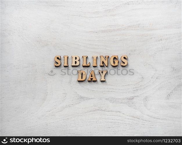 Wooden letters of the alphabet in the form of the words SIBLING DAY on the table. Beautiful card. Isolated background, wooden surface. Congratulations for relatives, friends and colleagues. Happy SIBLING DAY. Beautiful card.